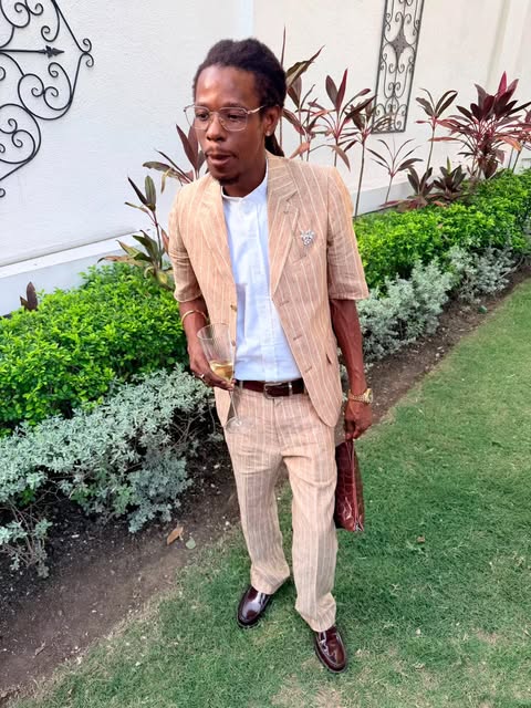 Man in a beige pinstripe suit and white shirt in a garden